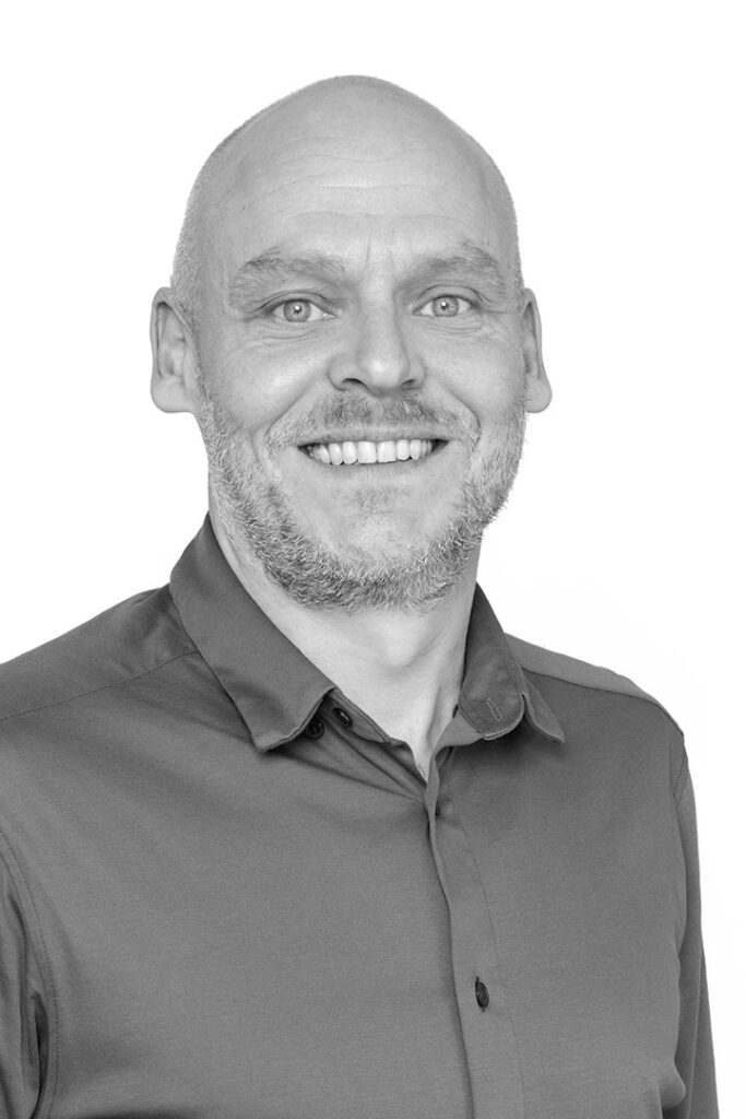 Portrætfoto i sort / hvid af salgssupport og kontakt i Lithomex Jan Guldberg Pedersen i grå skjorte på hvid baggrund